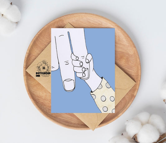 Baby Grip greeting card on a wooden plate with kraft envelope