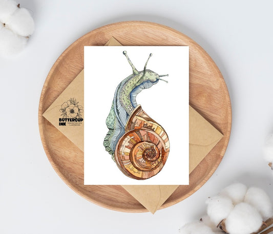 Snail watercolor greeting card on a wooden plate with kraft envelope